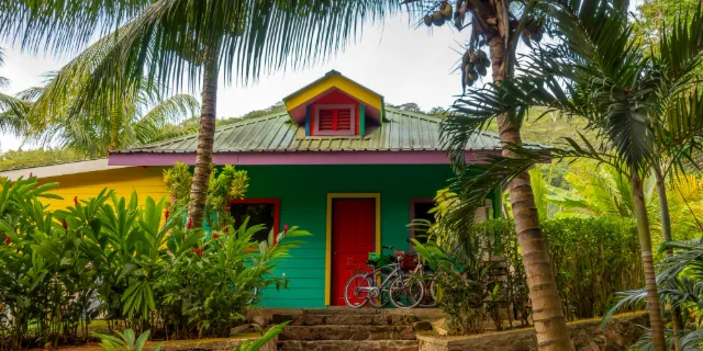Case créole verte à porte rouge sous les cocotiers, dans un jardin tropical de gîte à La Réunion