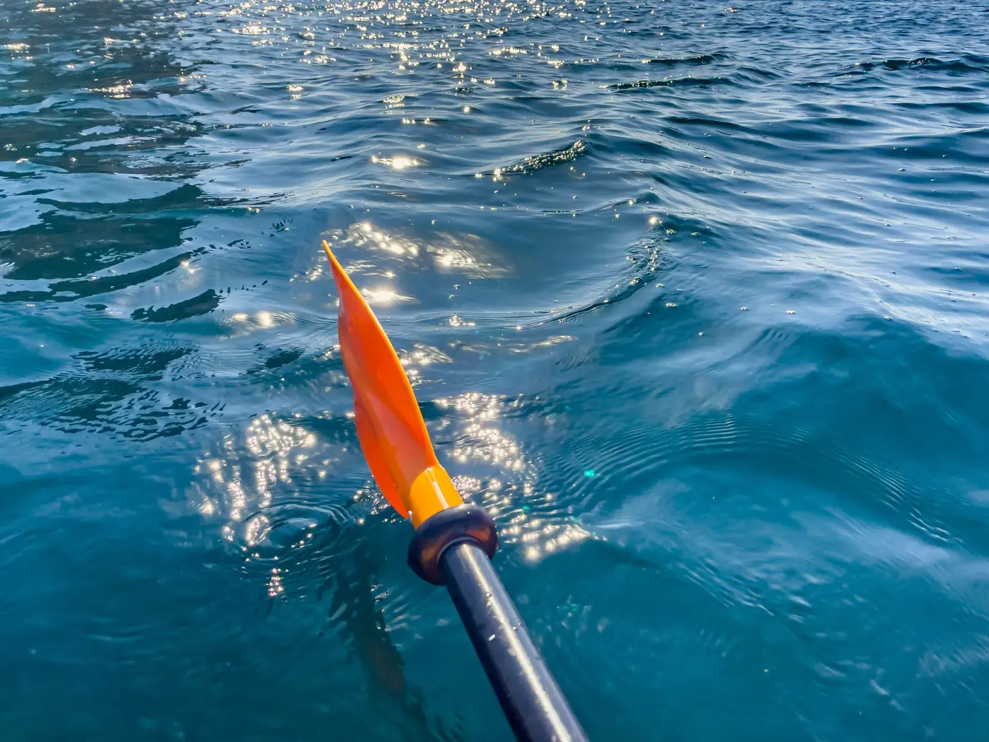Pagaie de kayak plongée dans l'eau claire, reflets du soleil