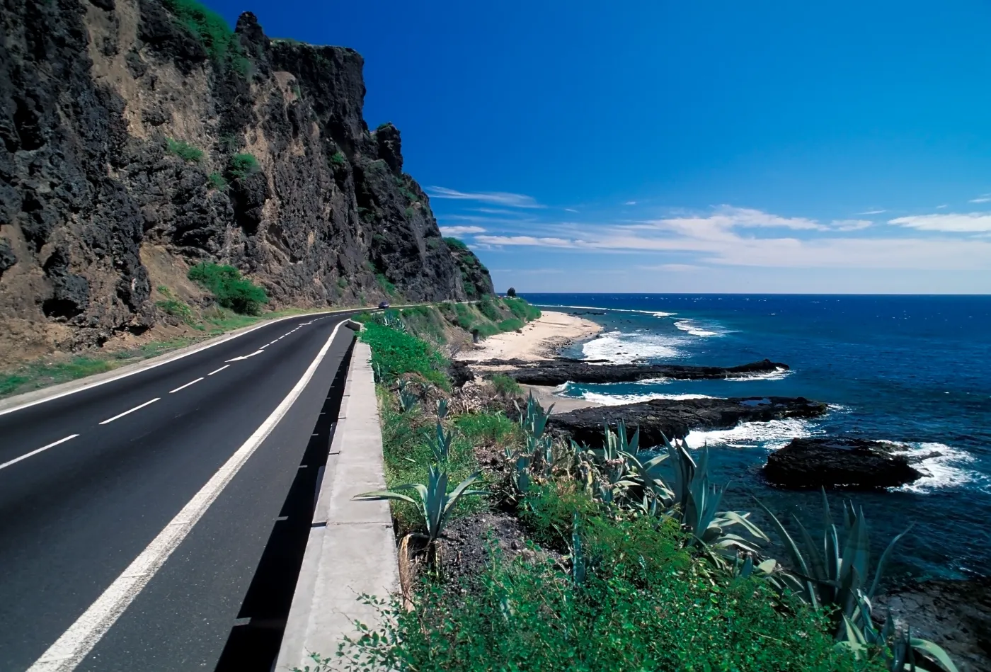 Route littorale de La Réunion longeant une falaise volcanique au-dessus de l'océan et d'une plage de sable
