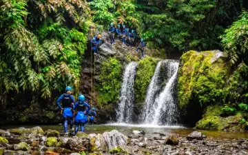 Groupe de canyoning descendant en rappel au pied d'une cascade